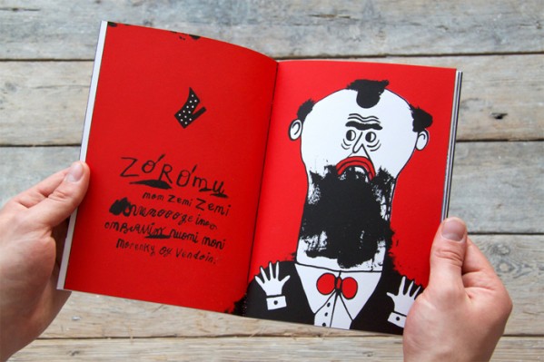 Joe Crocker’s book Vendoin being held open by two hands showing bright red pages with an illustration