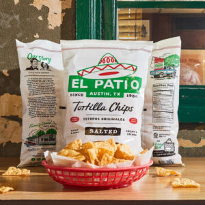 Three El Patio tortilla chip bags on a table with a basket full of chips in front of them